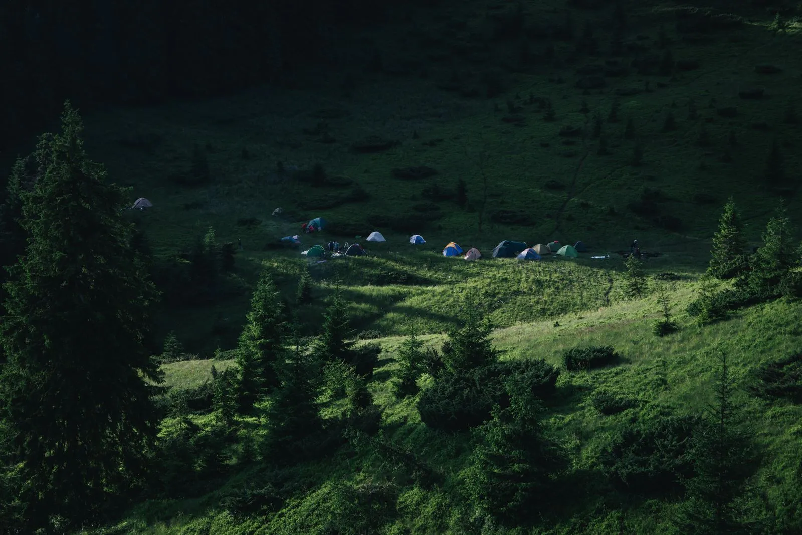 A peaceful camping site nestled in the lush green mountains of Romania, showcasing tents and nature's beauty.